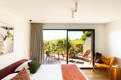 a bedroom with a bed and a view of a patio at Hôtel & Spa Version Maquis Citadelle in Bonifacio