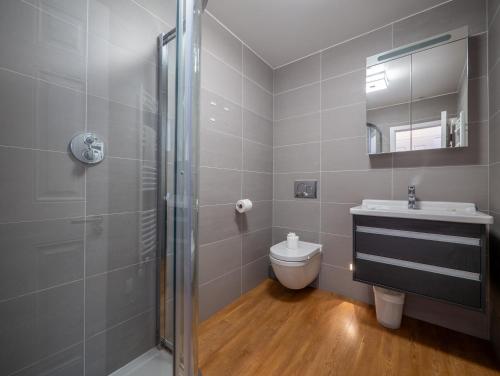 a bathroom with a shower and a toilet and a sink at Riverside Apartment with Stunning Views & Patio in Dartmouth