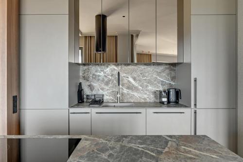 a kitchen with white cabinets and a marble counter top at Blue Mandarin Riverside Premium Sauna & Gym in Gdańsk