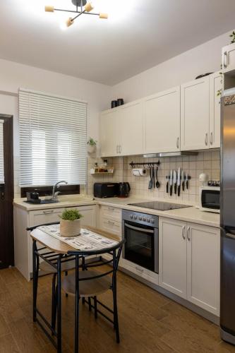 a kitchen with white cabinets and a table in it at THETIS Luxury House in Nikiti