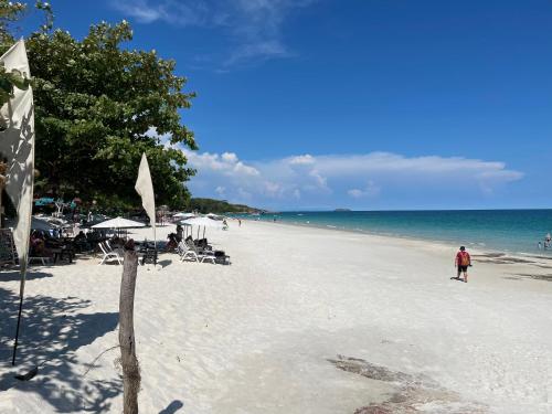 a beach with chairs and people on the water at TipThong Hut in Rayong