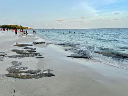 a group of people on a beach near the water at TipThong Hut in Rayong
