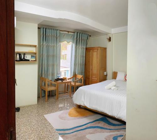 a bedroom with a bed and a table and chairs at Khách Sạn Tiến Loan in Hòa Bình