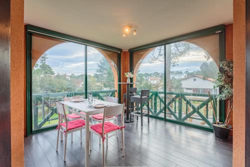 - une salle à manger avec une table, des chaises et de grandes fenêtres dans l'établissement Le Landais Wifi Terrasse Plage, à Tarnos