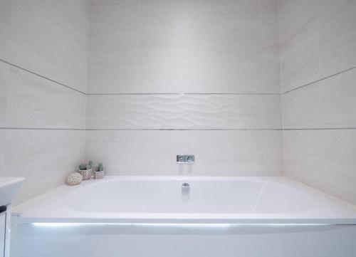 a white bath tub in a white bathroom at Large Riverside Retreat With Panoramic Dart Views in Dartmouth