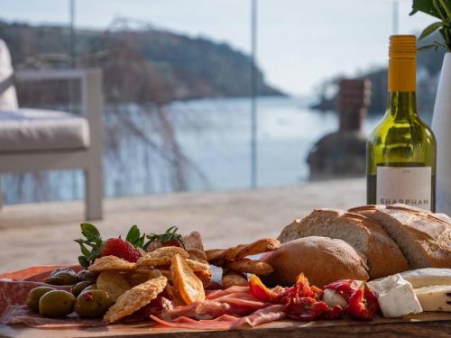 a plate of food with bread and a bottle of wine at Large Riverside Retreat With Panoramic Dart Views in Dartmouth