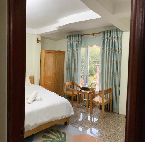 a bedroom with a bed and a table and a window at Khách Sạn Tiến Loan in Hòa Bình