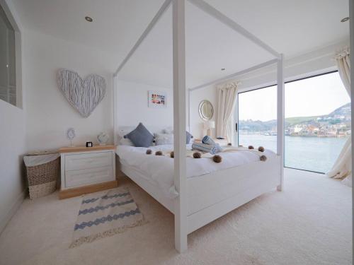 a bedroom with a white bed and a large window at Large Riverside Retreat With Panoramic Dart Views in Dartmouth