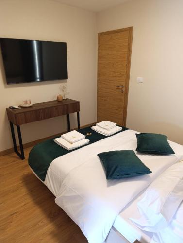 a bedroom with a large bed with a television on the wall at Apartmani Leburic in Prnjavor