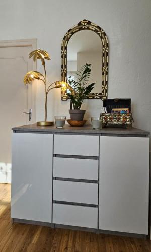 - une commode blanche avec un miroir au-dessus dans l'établissement Nid douillet dans le village de Marcillac-Vallon, à Marcillac-Vallon