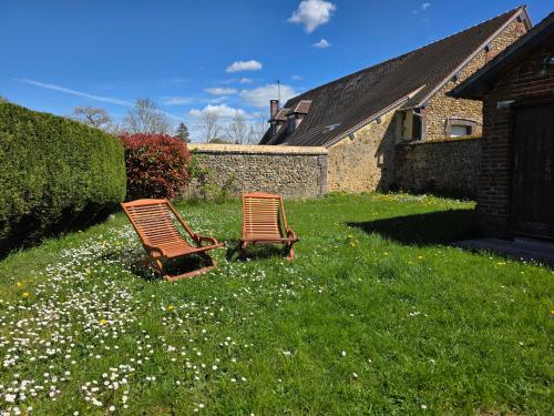 two chairs sitting in a yard with flowers at Évasion cosy au cœur du Perche in Boissy-lès-Perche