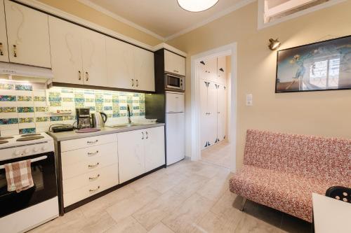 a kitchen with white cabinets and a couch in a room at Palaiopolis Maison by Konnect, Mon Repos Corfu in Corfu Town