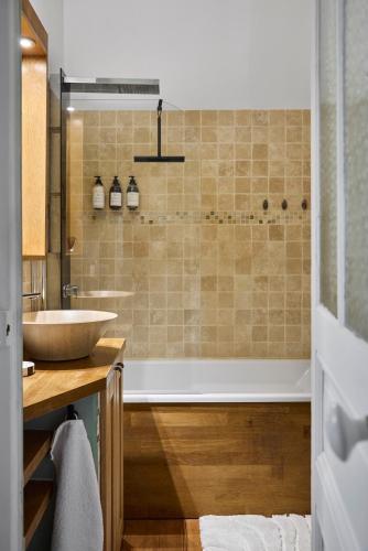 une salle de bain avec un lavabo et une baignoire dans l'établissement Le Jardin Secret - 2 chambres & Parking Offert, à Nantes