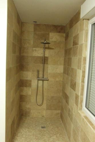 La salle de bains carrelée est pourvue d'une douche avec un tuyau. dans l'établissement Au jardin d'Eden, à Cuchery