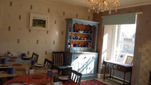 a dining room with a table and a chandelier at Argyle Guest House in Tomintoul