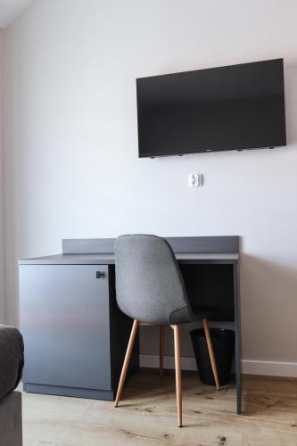 a desk with a chair and a television on a wall at W64 Apartamenty in Płock