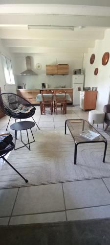 Il comprend un salon avec des tables et des chaises ainsi qu'une cuisine. dans l'établissement Gîte des Pommiers, à Sainte-Eulalie