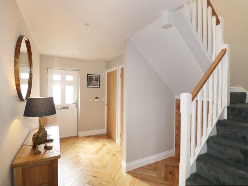 a hallway with stairs and a table with a lamp at Farm View House in Melton Mowbray
