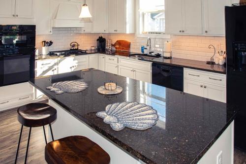 a kitchen with a black counter top with stools at Millville by the Sea- 23923 Pembroke Lane in Millville