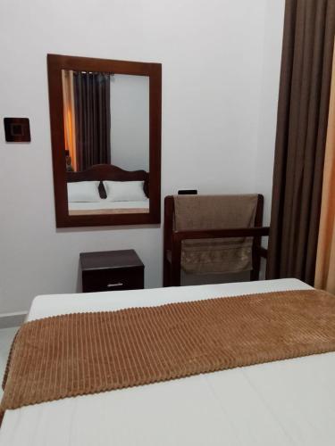 a bedroom with a bed and a mirror and a chair at Luana Holiday Bungalow in Bandarawela