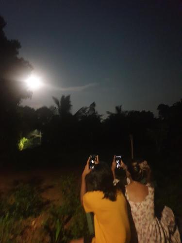 two people taking pictures of the moon at night at Water Pearl in Kosgama