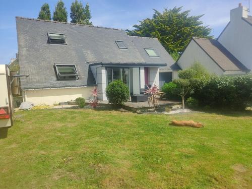 a dog laying on the grass in front of a house at Parc Faou in Erdeven