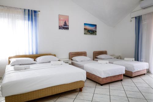 three beds in a room with white walls at Apartments Djukic in Tivat