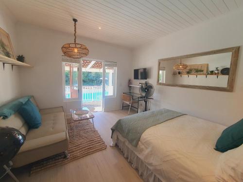 a bedroom with a bed and a couch and a mirror at Plett Pool Villa in Plettenberg Bay