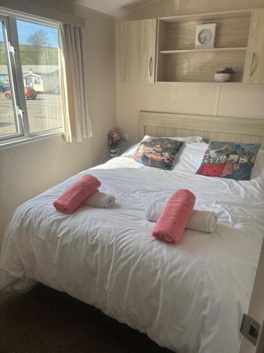a white bed with two pink pillows on it at Newquay Bay - 3-Bed Caravan - Sleeps 6 in Newquay