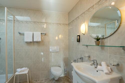 a bathroom with a sink and a toilet and a mirror at Landhotel Gockelwirt in Eisenberg