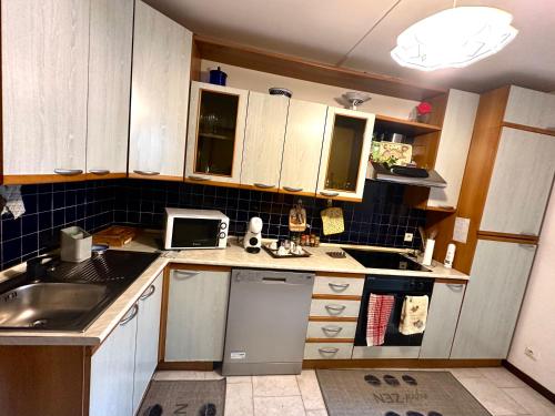 Elle comprend une petite cuisine avec des placards en bois et un évier. dans l'établissement Mini-villa située à 5 minutes de la plage de Pinarello à pieds, à Pinarellu