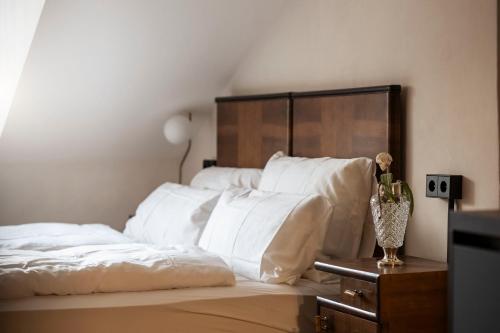 a bed with white sheets and a vase of flowers on a table at Ansitz Thierburg Suites in Merano