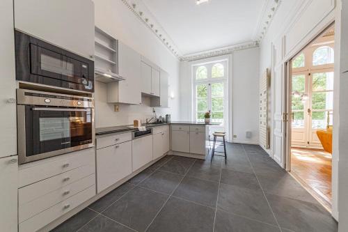 Una cocina con gabinetes blancos y una ventana grande. en Le Roi René - XIXe siècle - Château, en Angers
