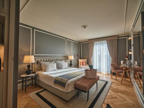 a bedroom with a large bed and a table and chairs at GA Palace Hotel & Spa, a XIXth-Century Villa in Porto
