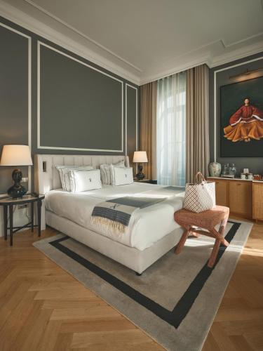 a bedroom with a large bed and a chair at GA Palace Hotel & Spa, a XIXth-Century Villa in Porto