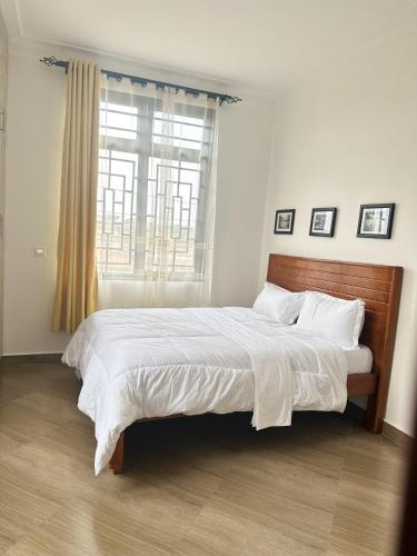 a bedroom with a bed with white sheets and a window at Zaya Residency in Kampala