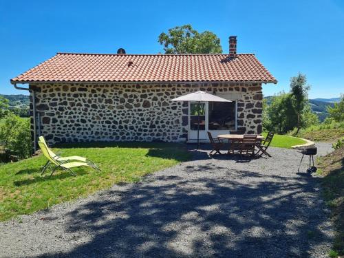 une petite maison en pierre avec une table et un parasol dans l'établissement Charming Gite avec beau panorama, à Arsac-en-Velay
