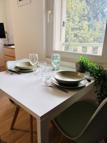 une table blanche avec des assiettes et des verres ainsi qu'une fenêtre dans l'établissement Studio Proche Gare & Centre Ville, à Castres