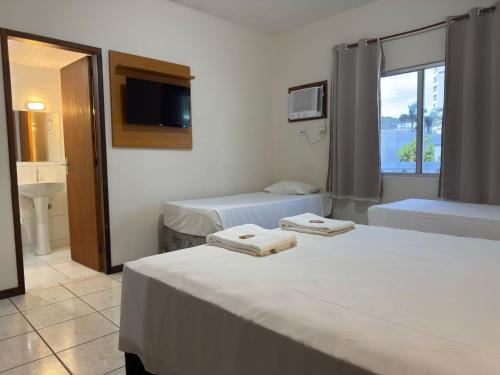 a hotel room with two beds and a television at Hotel Graju Itajaí in Itajaí
