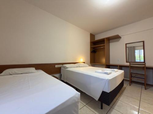 a hotel room with two beds and a chair at Hotel Graju Itajaí in Itajaí
