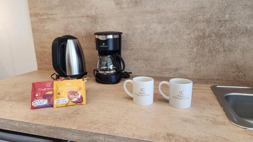 three coffee mugs sitting on a counter next to a coffee maker at Grec Suites Dafni, Athens by GrecCollection in Athens
