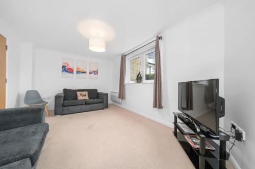 a living room with a couch and a tv at Saughton Suite with views of Water of Leith in Edinburgh