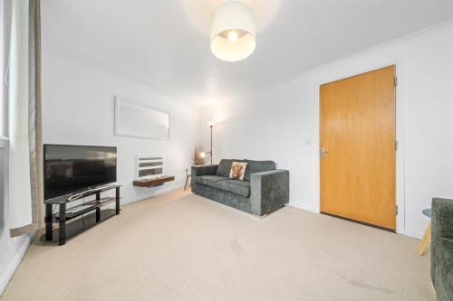 a living room with a couch and a television at Saughton Suite with views of Water of Leith in Edinburgh
