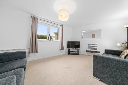 a living room with a couch and a tv and a window at Saughton Suite with views of Water of Leith in Edinburgh