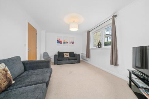 a living room with a couch and a tv at Saughton Suite with views of Water of Leith in Edinburgh