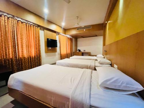 a hotel room with three beds and a tv at PLA Rathna Residency Trichy in Tiruchchirāppalli
