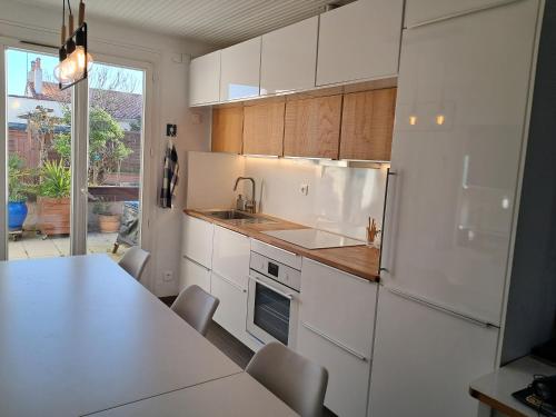 La cuisine blanche est équipée d'un évier et d'un réfrigérateur. dans l'établissement Les portes du soleil, à Les Sables-dʼOlonne