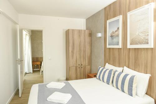 a bedroom with a white bed and a wooden wall at Faro Heart Suites in Faro
