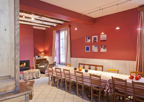 a dining room with red walls and a table and chairs at Gîtes de Baya in Ohey