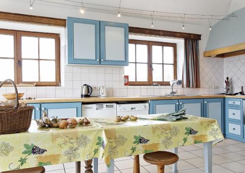 a kitchen with blue cabinets and a table with fruit on it at Gîtes de Baya in Ohey